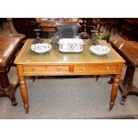 A late Victorian golden oak writing table, having leather inset top above two drawers with
