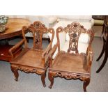 A pair of Chinese hardwood chairs, having carved and pierced foliate decoration, raised on