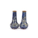 A pair of Doulton baluster vases, having raised floral decoration on a mottled blue, brown and green