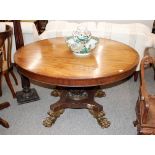 An early 19th Century mahogany circular tilt top dining table, raised on a leaf carved baluster