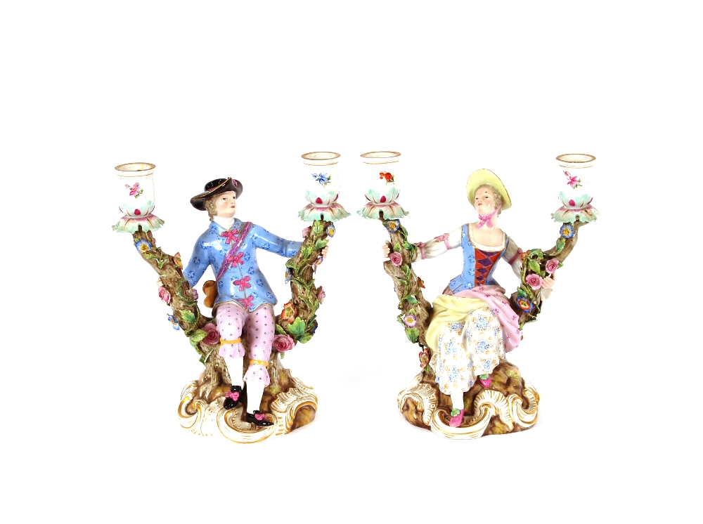 A pair of 19th Century Meissen porcelain figural candlesticks, depicting maid and youth seated on