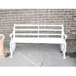 A painted metal garden seat, having scrolled branch work and dog's head decoration, wooden slats,