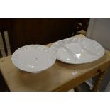 A white glazed serving platter and a similar cake