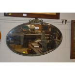 An unframed bevel edged oval wall mirror with face