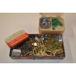 A tin of various costume jewellery; a wrist watch