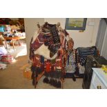 A camel seat with rugs and wooden stand