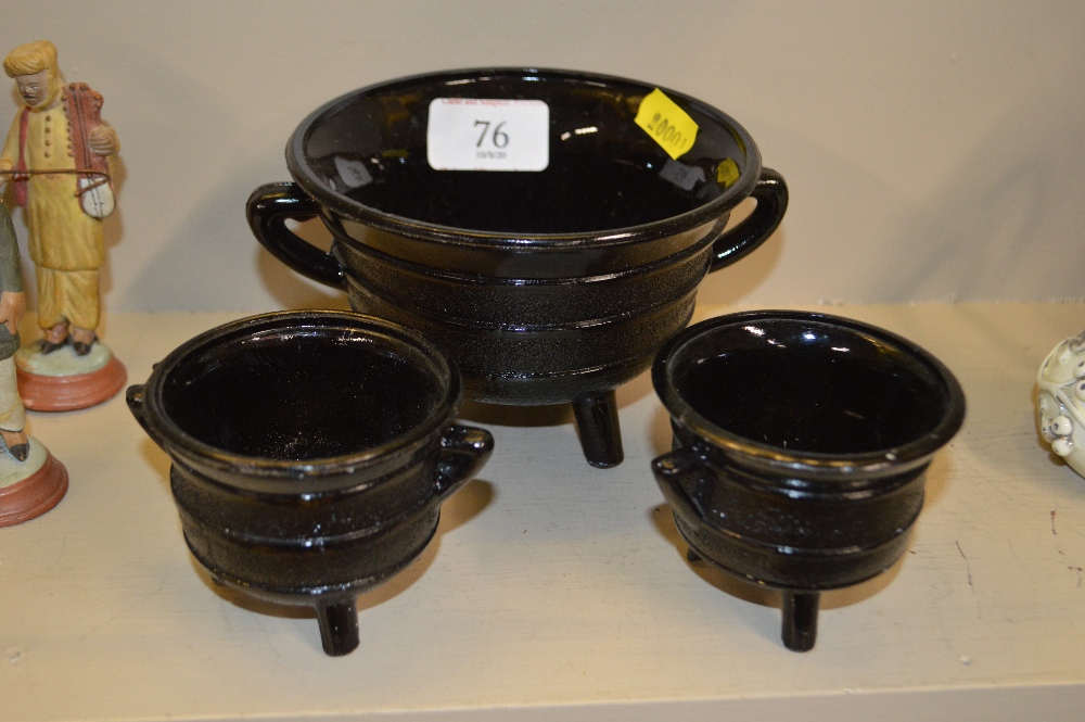Three pressed black glass bowls, each raised on th