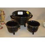 Three pressed black glass bowls, each raised on th