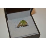 A silver peridot set ring with flower head form