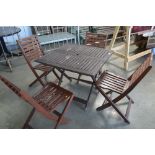 A teak garden table and four folding chairs