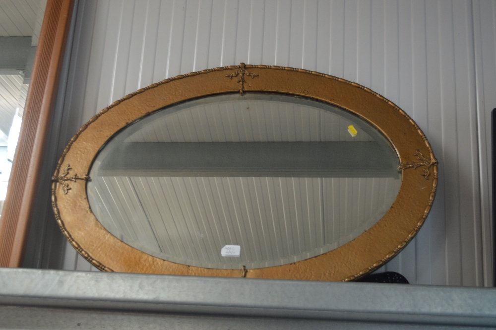 A gilt metal oval and bevelled edge wall mirror