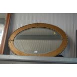 A gilt metal oval and bevelled edge wall mirror