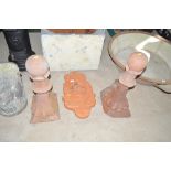 A pair of terracotta finials and a wall plaque