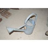 A galvanised watering can, complete with rose