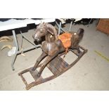 A wooden rocking horse with leather saddle