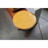 A light oak circular topped table raised on tripod