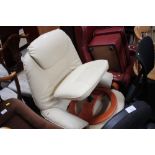 A cream upholstered swivel chair and matching foot