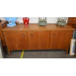A teak sideboard, fitted central cupboards with sh