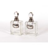 A pair of square glass decanters with white metal
