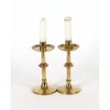 A pair of brass Arts & Crafts design candlesticks