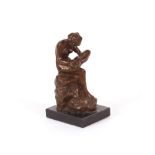 A bronze figure of a naked maiden seated on a rock