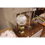 A brass oil lamp with etched glass shade