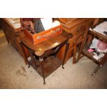 An Arts & Crafts oak two tier table raised on pad