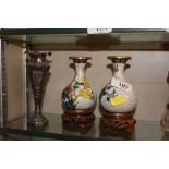 A pair of oriental cloisonné vases on carved woode