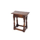 An oak joint stool, with overhanging top and moulded frieze, raised on turned baluster supports
