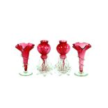 A pair of cranberry glass trumpet shaped posy vases, with clear glass raised decoration and spread