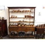 An 18th Century oak dresser, having open plate rack above three drawers, pot board below raised on