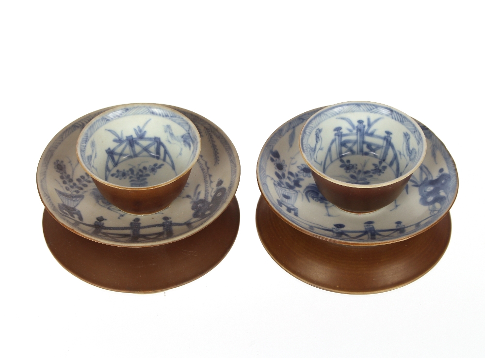 A pair of Chinese tea bowls and saucers, with Buddhist chicken decoration and brown under glaze