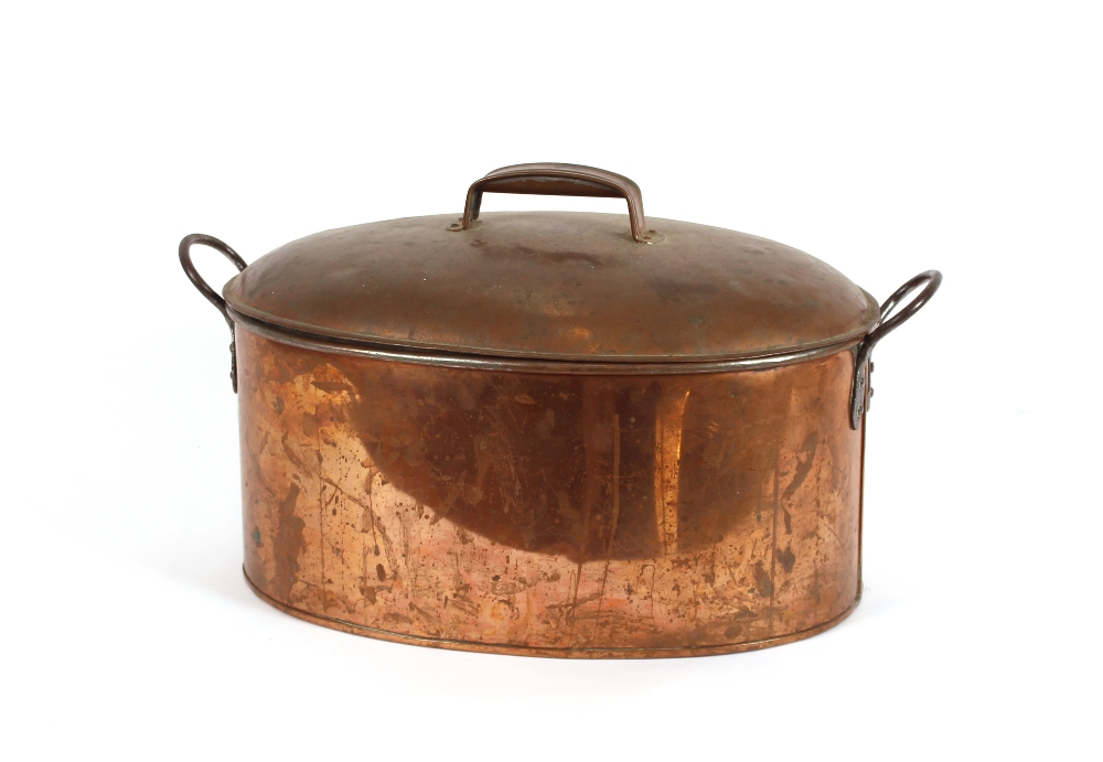 A large copper fish kettle, flanked by iron loop handles, 53cm long