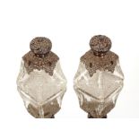 A pair of Edwardian heavy cut glass scent bottles, of waisted form, hobnail cut bases with silver