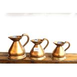 Three antique copper baluster measuring jugs, half pint, one gill and half a gill