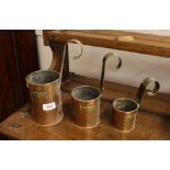 Three graduated copper measures, with brass loop handles, two pint, one pint, and half pint