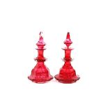 A pair of cranberry glass cologne bottles, of stepped form having spike shaped stoppers, 22cm high