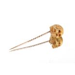 A bone and yellow metal stick pin, in the form of a skull