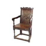 An antique oak wainscot chair, the scrolled cresting rail bearing date 1642, foliate carved panel