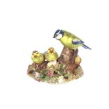 A Royal Crown Derby bone china group of birds, perched on a branch with floral encrusted base,