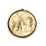 A small carved plaster plaque, having relief classical decoration in brass frame, 12.5cm dia.