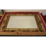 An antique gilt framed wall mirror, having foliate scroll decoration and flower heads, fitted