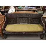 An antique carved oak settle, having triple panel back 171cm wide