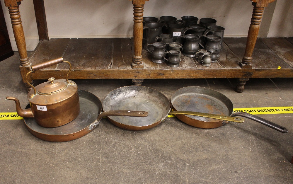 An antique copper frying pan, with brass handle; two others with iron loop handles; and a copper