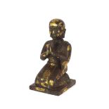 A Tibetan bronze and gold splash kneeling figure of a priest at prayer, dark brown patination,