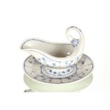An unusual 19th Century blue and white sauce boat, on integral stand, having scroll handle and