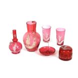 A collection of cranberry Mary Gregory style decorated glass, including two ewers, beakers, ring