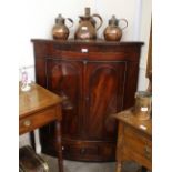 A 19th Century mahogany bow fronted corner cupboard, the interior shelves enclosed by a pair of