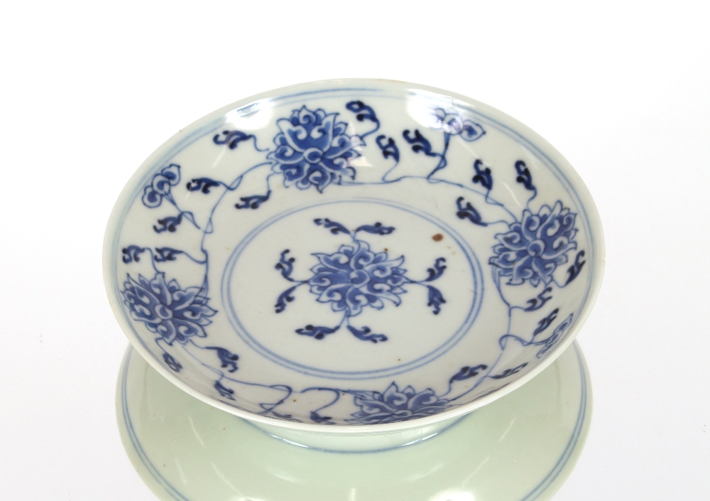 An 18th Century Chinese saucer dish, decorated in under glaze blue with flower heads