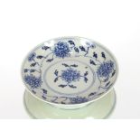 An 18th Century Chinese saucer dish, decorated in under glaze blue with flower heads